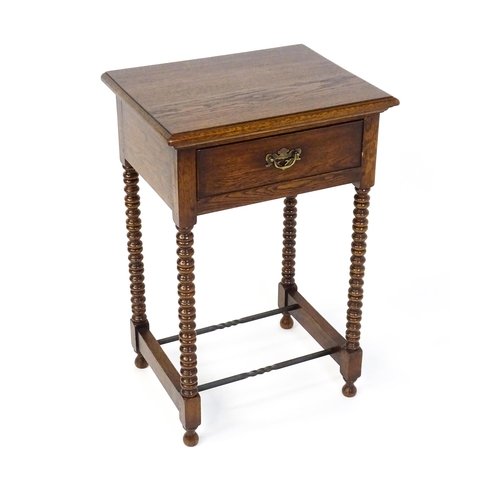 1591 - A mid 20thC oak side table with a moulded top above a short frieze drawer above four bobbin turned l... 