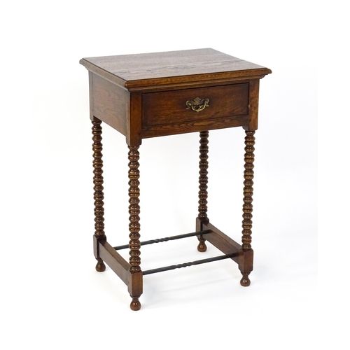 1591 - A mid 20thC oak side table with a moulded top above a short frieze drawer above four bobbin turned l... 