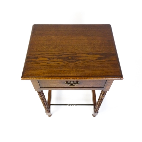 1591 - A mid 20thC oak side table with a moulded top above a short frieze drawer above four bobbin turned l... 