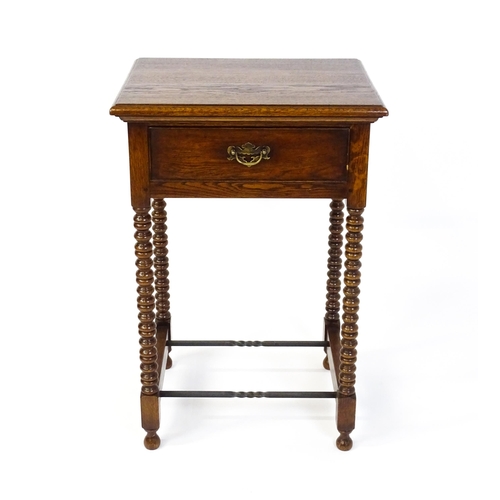 1591 - A mid 20thC oak side table with a moulded top above a short frieze drawer above four bobbin turned l... 