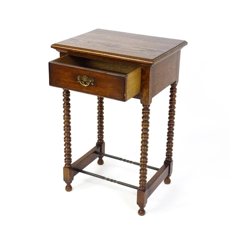 1591 - A mid 20thC oak side table with a moulded top above a short frieze drawer above four bobbin turned l... 