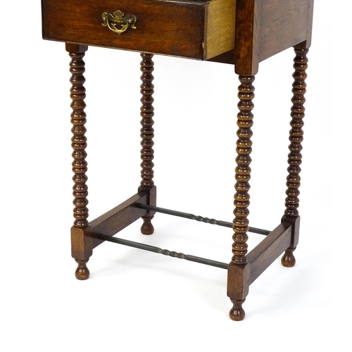 1591 - A mid 20thC oak side table with a moulded top above a short frieze drawer above four bobbin turned l... 