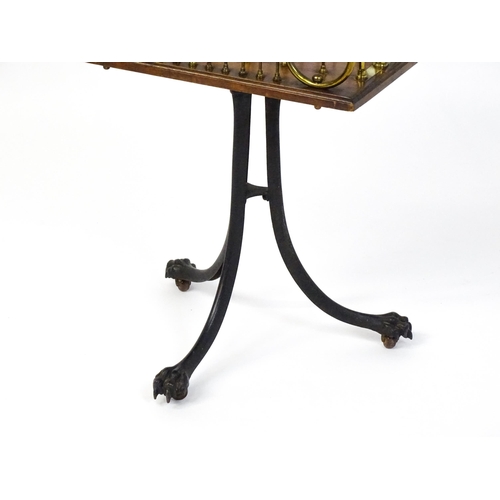 1595 - An early / mid 20thC brass and mahogany Canterbury raised on an iron base with lions paw feet. 16