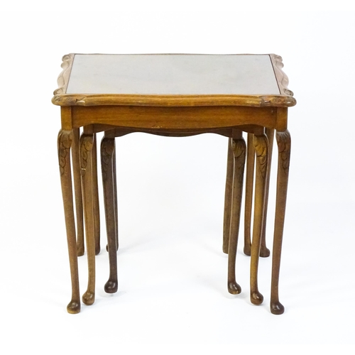 1599 - A mid / late 20thC nest of three burr walnut topped tables raised on acanthus carved legs terminatin... 