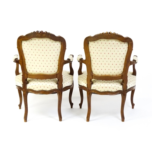 1607 - A pair of Louis XV style fauteuil open armchairs with floral carved cresting rails, swept arms,  uph... 