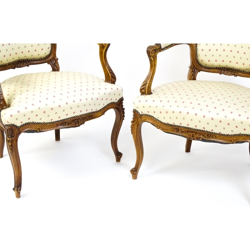 1607 - A pair of Louis XV style fauteuil open armchairs with floral carved cresting rails, swept arms,  uph... 