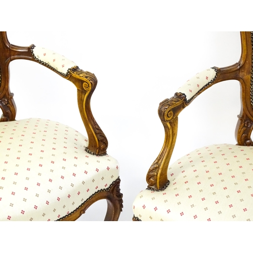 1607 - A pair of Louis XV style fauteuil open armchairs with floral carved cresting rails, swept arms,  uph... 