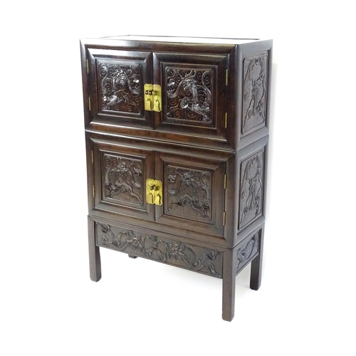 1614 - An oriental rosewood cabinet of three tiers, the top two sections having panelled carved doors depic... 