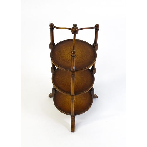 1619 - A mid 20thC walnut three tier cake stand with leather topped circular shelves. 26