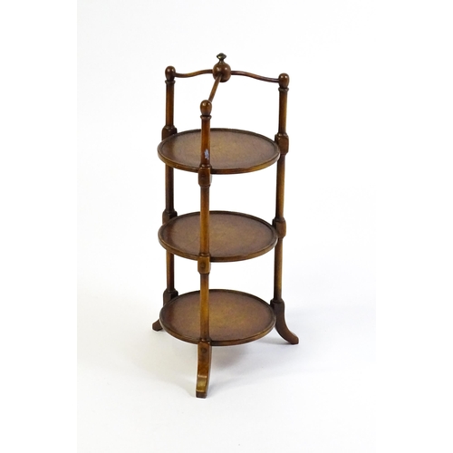 1619 - A mid 20thC walnut three tier cake stand with leather topped circular shelves. 26