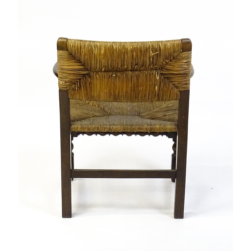 1622 - An early 20thC Wylie & Lochhead elbow chair with a rush back and envelope rush seat, carved roundels... 