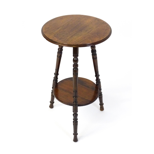 1628 - A late 19thC / early 20thC walnut occasional table with two circular tiers raised on three ring turn... 