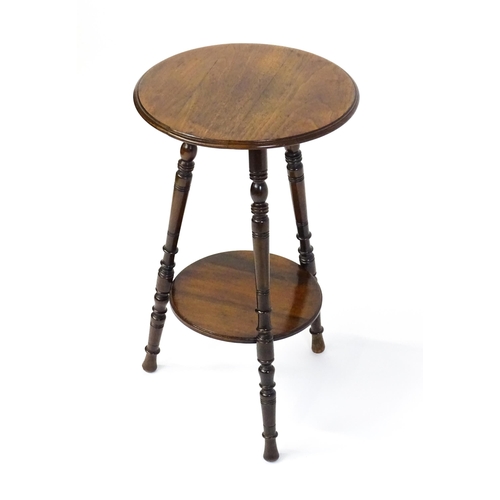 1628 - A late 19thC / early 20thC walnut occasional table with two circular tiers raised on three ring turn... 