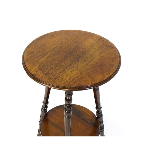 1628 - A late 19thC / early 20thC walnut occasional table with two circular tiers raised on three ring turn... 