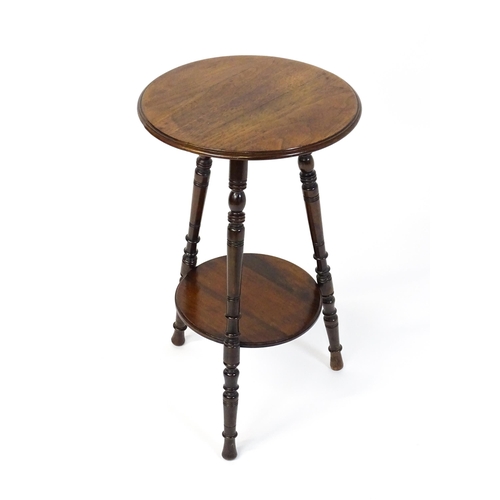 1628 - A late 19thC / early 20thC walnut occasional table with two circular tiers raised on three ring turn... 