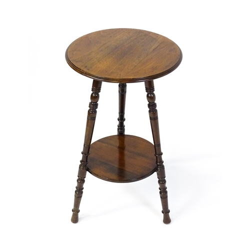 1628 - A late 19thC / early 20thC walnut occasional table with two circular tiers raised on three ring turn... 