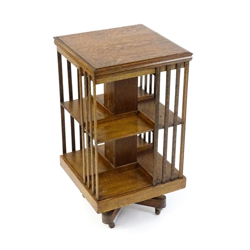 1632 - An early 20thC oak revolving bookcase with a figured top above two tiers of four shelves, the sides ... 