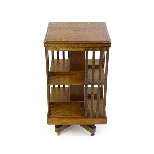 1632 - An early 20thC oak revolving bookcase with a figured top above two tiers of four shelves, the sides ... 