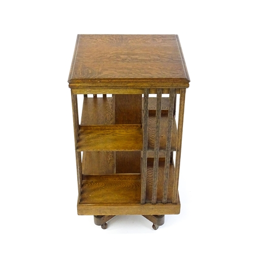 1632 - An early 20thC oak revolving bookcase with a figured top above two tiers of four shelves, the sides ... 