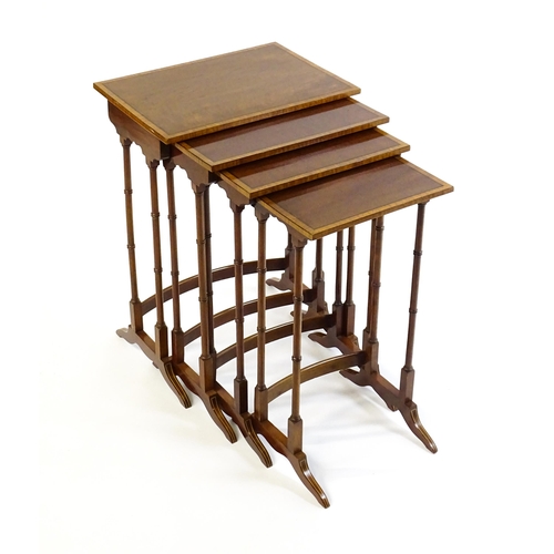 1634 - A nest of four early 20thC tables with crossbanded mahogany tops raised on turned tapering legs and ... 