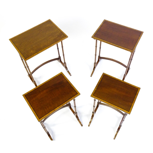 1634 - A nest of four early 20thC tables with crossbanded mahogany tops raised on turned tapering legs and ... 