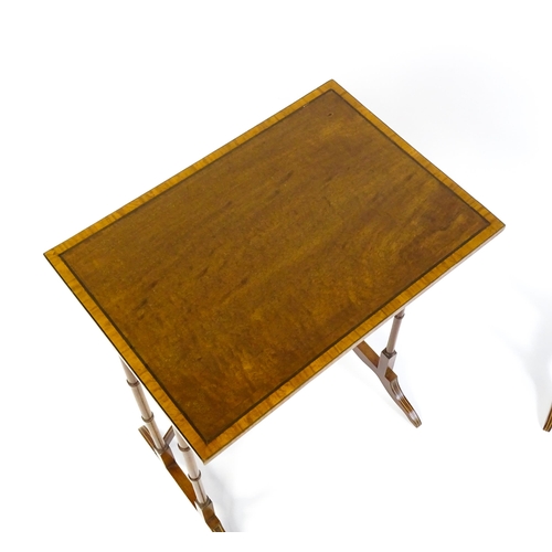 1634 - A nest of four early 20thC tables with crossbanded mahogany tops raised on turned tapering legs and ... 