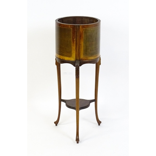 1638 - An early 20thC mahogany jardinière with a barrel top raised on three carved cabriole legs united by ... 