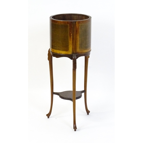 1638 - An early 20thC mahogany jardinière with a barrel top raised on three carved cabriole legs united by ... 