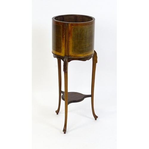 1638 - An early 20thC mahogany jardinière with a barrel top raised on three carved cabriole legs united by ... 