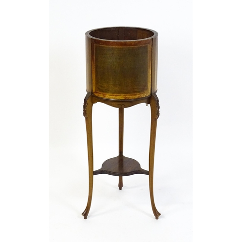 1638 - An early 20thC mahogany jardinière with a barrel top raised on three carved cabriole legs united by ... 