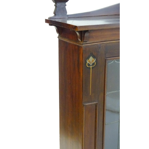 1647 - An Art Nouveau mahogany cabinet with a shaped upstand and two leaded glass doors with floral marquet... 