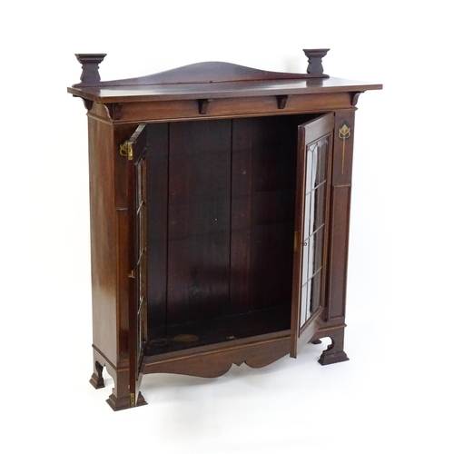 1647 - An Art Nouveau mahogany cabinet with a shaped upstand and two leaded glass doors with floral marquet... 