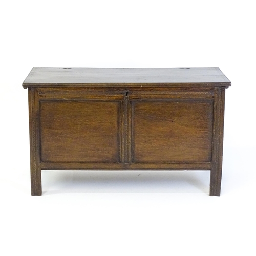 1651 - A late 17thC / early 18thC oak coffer with a hinged lid above a panelled and carved front raised on ... 