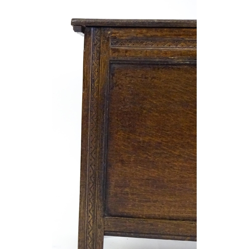 1651 - A late 17thC / early 18thC oak coffer with a hinged lid above a panelled and carved front raised on ... 