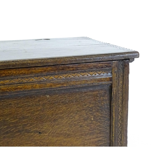 1651 - A late 17thC / early 18thC oak coffer with a hinged lid above a panelled and carved front raised on ... 