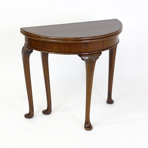 1660 - A 20thC mahogany demi lune card table with a hinged top opening to show a baize playing surface rais... 