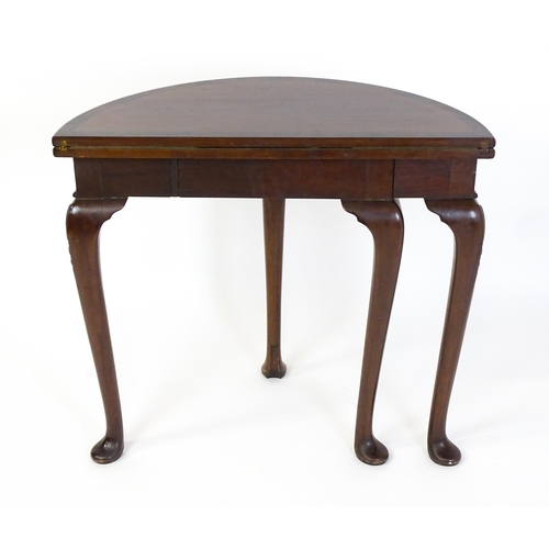 1660 - A 20thC mahogany demi lune card table with a hinged top opening to show a baize playing surface rais... 