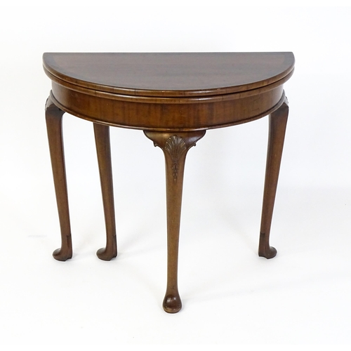 1660 - A 20thC mahogany demi lune card table with a hinged top opening to show a baize playing surface rais... 