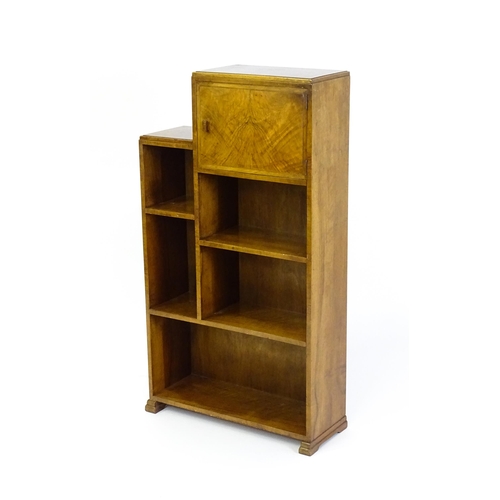 1667 - A mid 20thC walnut Art Deco bookcase / cabinet with open fronted shelves and raised on stepped feet.... 