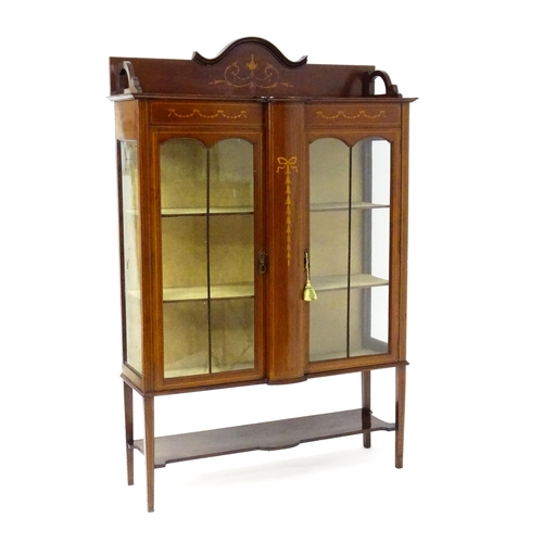 1670 - An Edwardian mahogany display cabinet with a shaped and moulded upstand, a satinwood inlaid frame wi... 