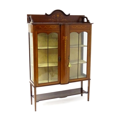 1670 - An Edwardian mahogany display cabinet with a shaped and moulded upstand, a satinwood inlaid frame wi... 