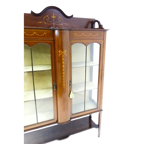 1670 - An Edwardian mahogany display cabinet with a shaped and moulded upstand, a satinwood inlaid frame wi... 