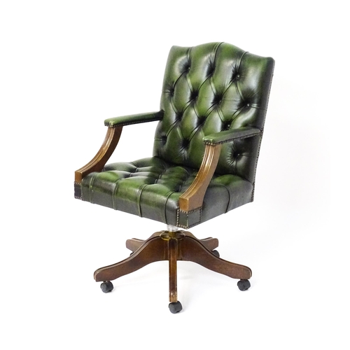 1684 - A late 20thC green leather captains chair with deep buttoned upholstery, reeded Gainsborough style a... 