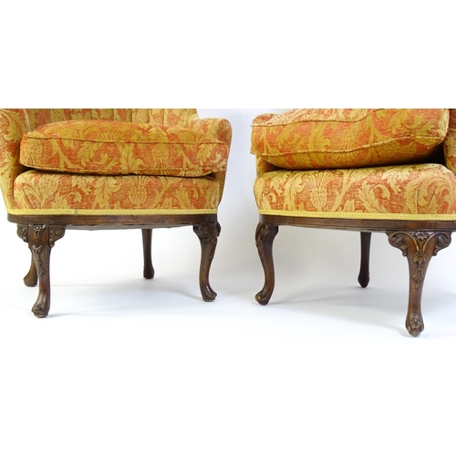 1685 - A pair of mid 20thC barrel back armchairs raised on acanthus carved cabriole legs terminating in car... 