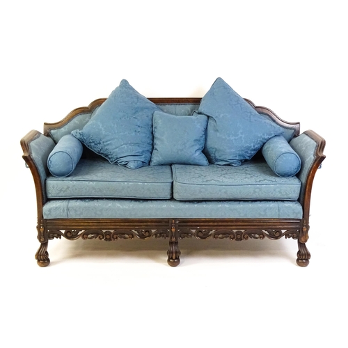 1687 - An early 20thC settee with a carved show wood frame and blue upholstery, the sofa having a carved an... 