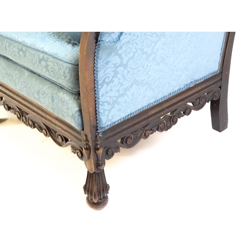 1687 - An early 20thC settee with a carved show wood frame and blue upholstery, the sofa having a carved an... 