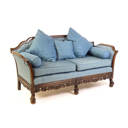 1687 - An early 20thC settee with a carved show wood frame and blue upholstery, the sofa having a carved an... 