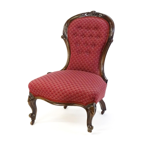 1696 - A late 19thC / early 20thC nursing chair with a deep buttoned spoon back adorned with a carved crest... 