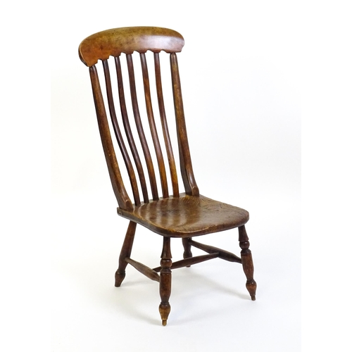 1746 - A 19thC lathe back nursing chair with a shaped elm seat raised on four turned tapering legs united b... 