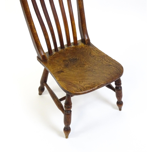 1746 - A 19thC lathe back nursing chair with a shaped elm seat raised on four turned tapering legs united b... 